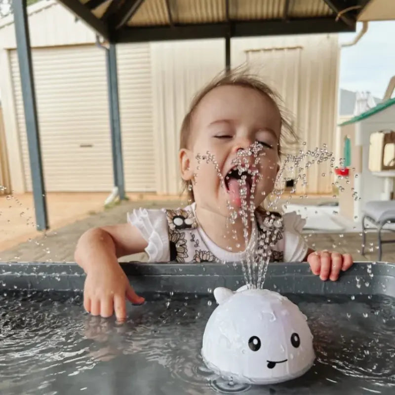 criança com Brinquedo Banho Interativo Para Bebê Luzes e Jatos D'água Baby Whale